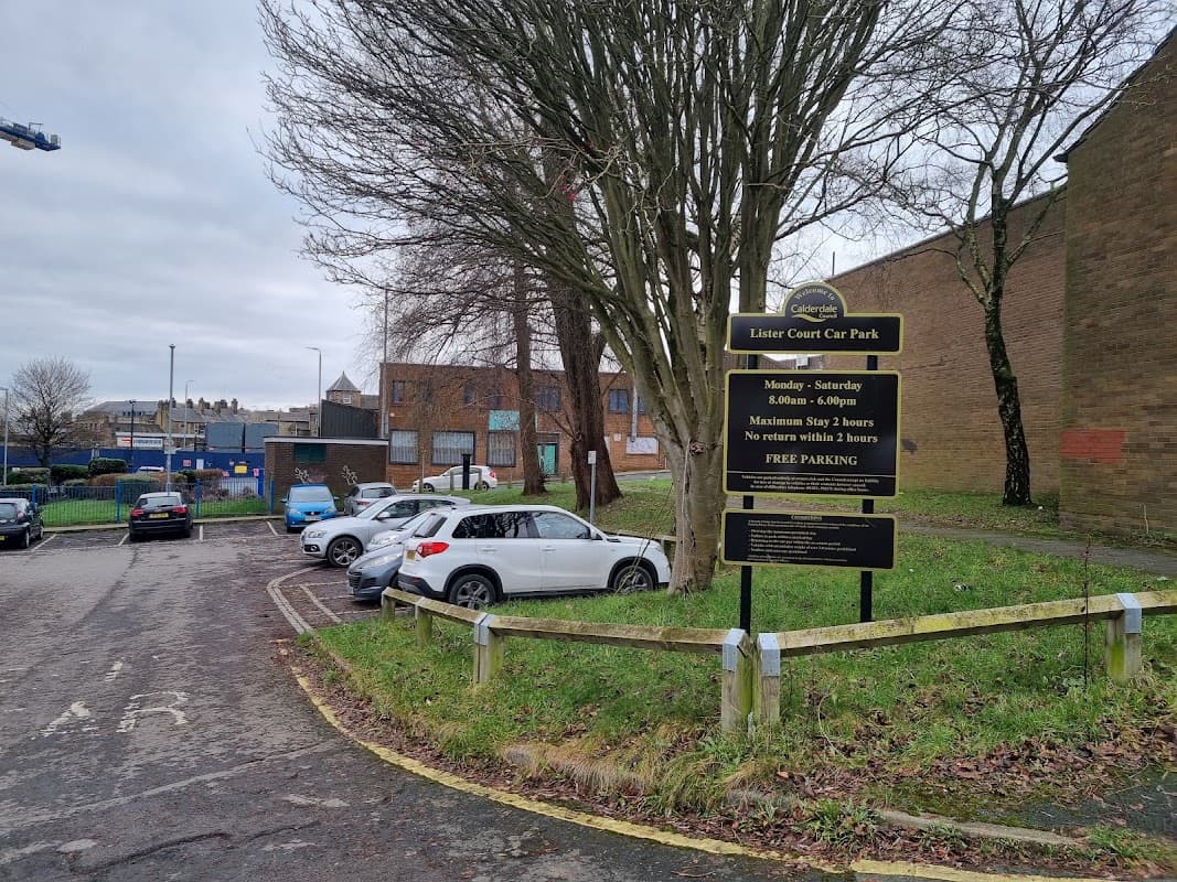 Lister Court Car Park sign with parking spaces, trees, and buildings in Exley, Yorkshire. Free parking available.