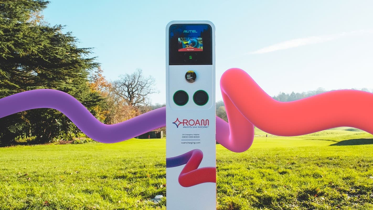 Roam Charging Station with a digital display, surrounded by greenery and colorful abstract shapes.