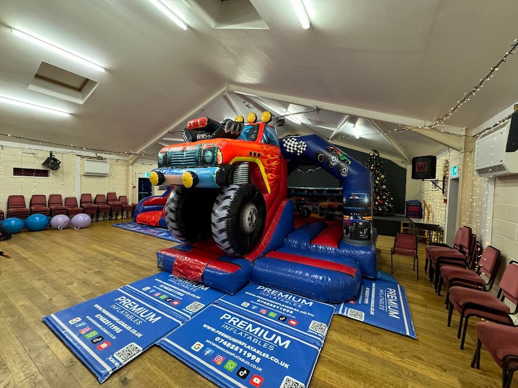 Brightly colored inflatable truck bouncer in a community hall with chairs and festive decorations.