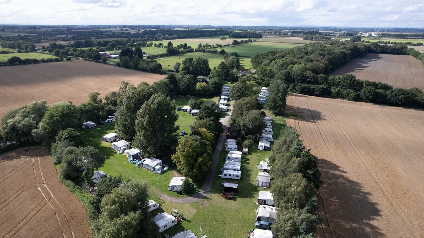 Aerial view of Fangfoss Park showing green fields, trees, and rows of caravans nestled in a rural setting.