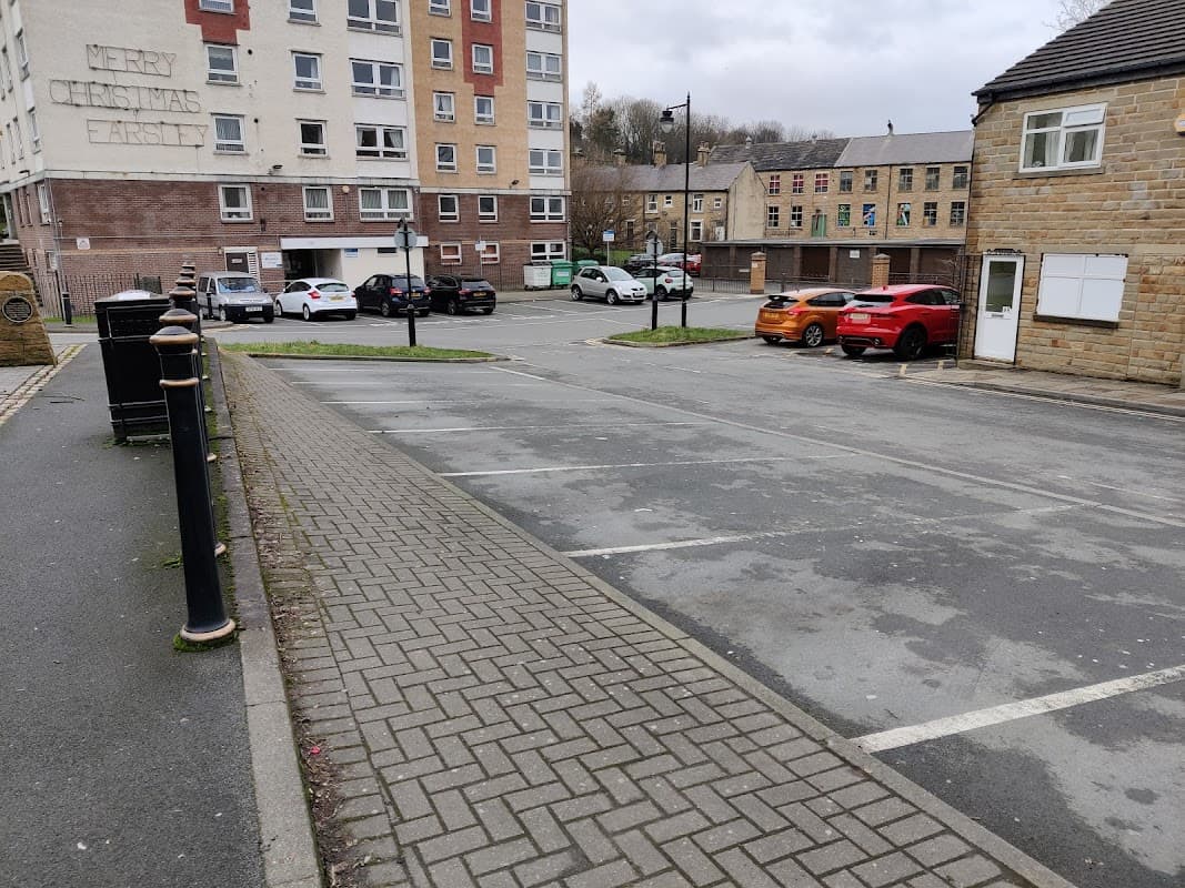 Pay & Display parking lot in Farsley, Yorkshire, with empty spaces, residential buildings, and parked cars.