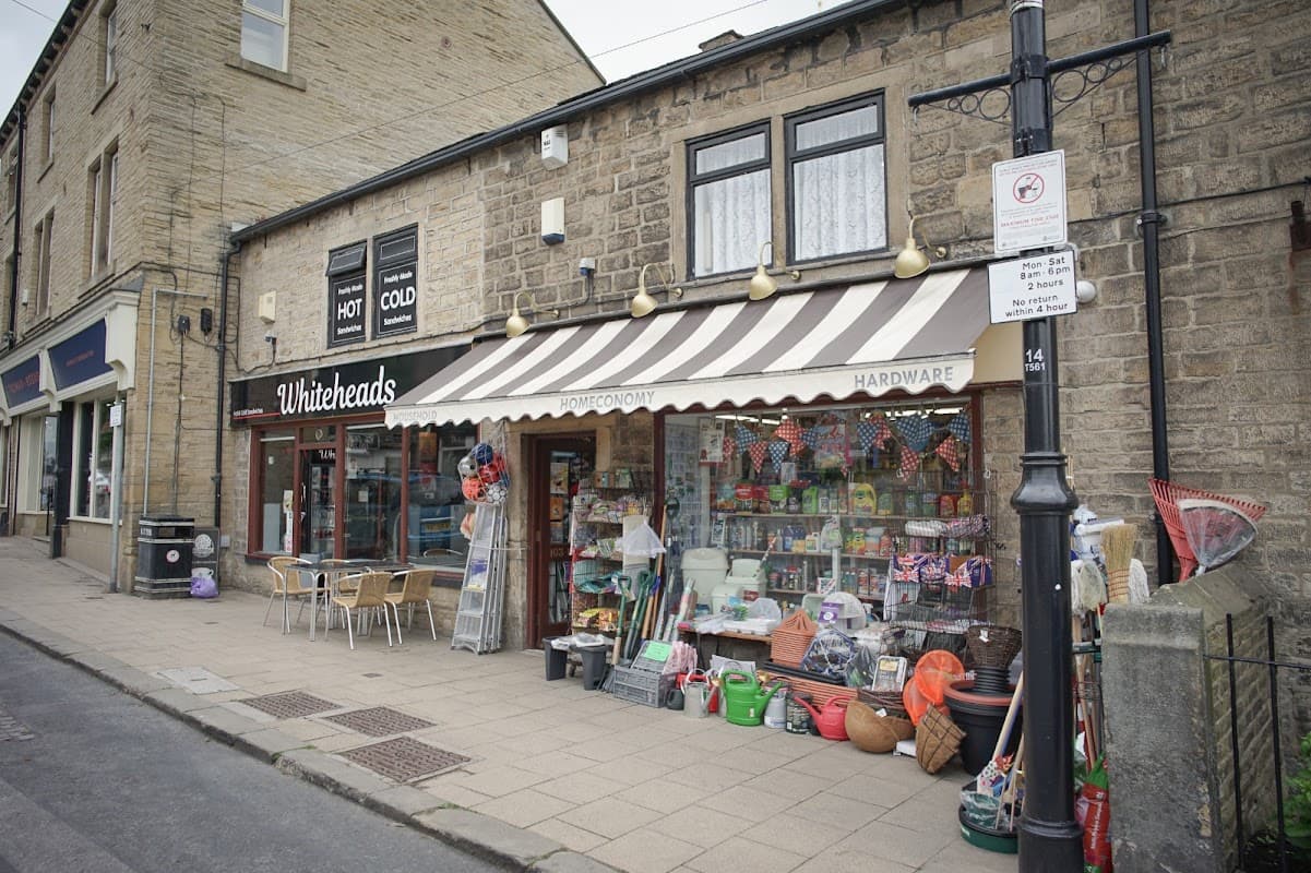 Ironmongers storefront with striped awning, colorful gardening supplies, and outdoor seating in Farsley, Yorkshire.