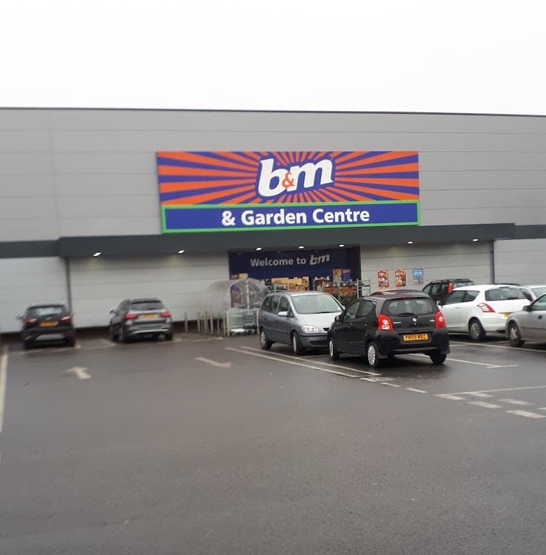 B&M & Garden Centre storefront with colorful signage and parked cars in a spacious retail park car park.