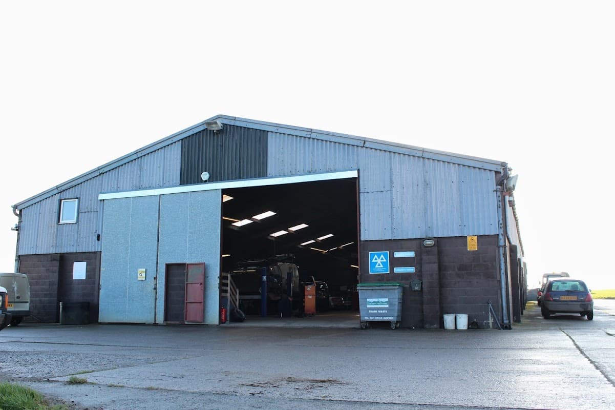 Large metal warehouse with an open front, featuring a sign for P A Blackburn Ltd, set in a rural area.