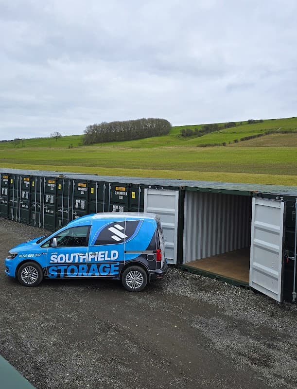Southfield Storage van parked beside storage containers with green hills in the background under a cloudy sky.