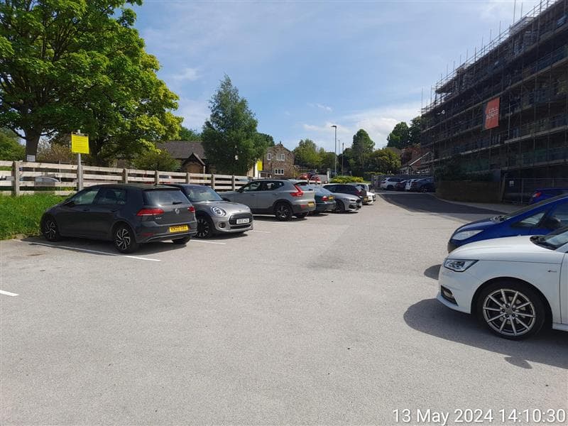 Pannal Village Hall car park with parked cars, greenery, and a building under construction in the background.