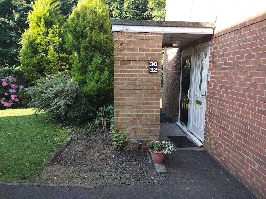 Brick entrance with house numbers 30 and 32, surrounded by greenery and flowering plants in Follifoot, Yorkshire.