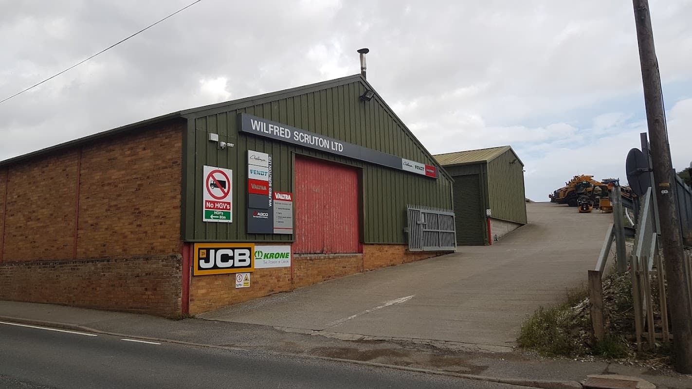 Wilfred Scruton Ltd building with red doors, signage, and parked machinery in Foxholes, North Yorkshire.