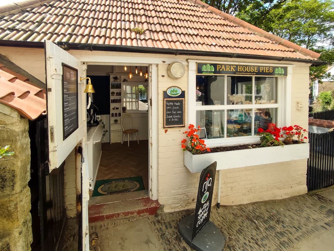 Quaint shopfront of Park House Pies with a welcoming entrance, flower boxes, and a sign displaying the shop name.