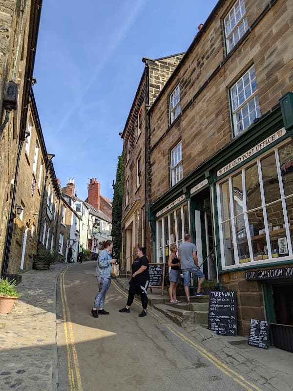 Busy street scene on Thorpe Lane, featuring charming stone buildings, a café, and people chatting outside.