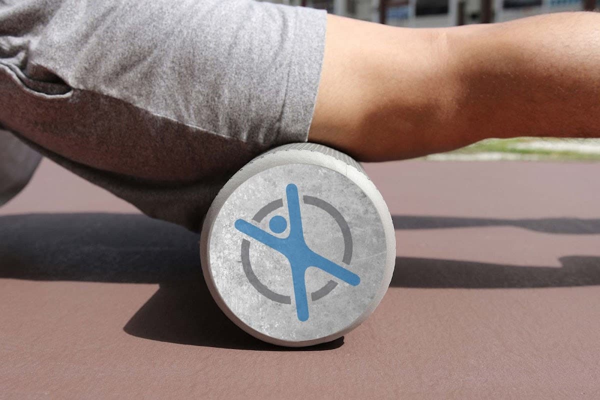 A person using a foam roller with a blue FLEX Pilates logo on a brown exercise mat.