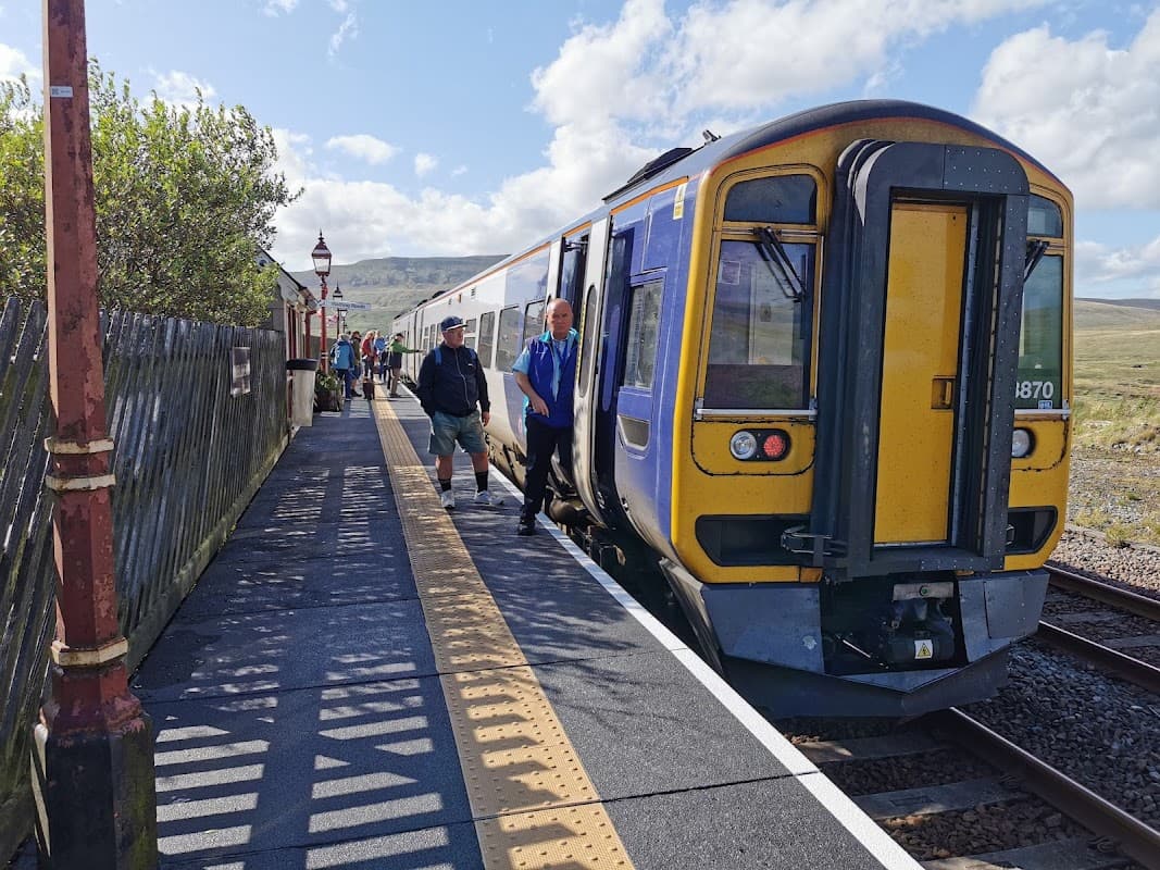 Ribblehead Visitor Centre with passengers disembarking from a train at a scenic Yorkshire station.