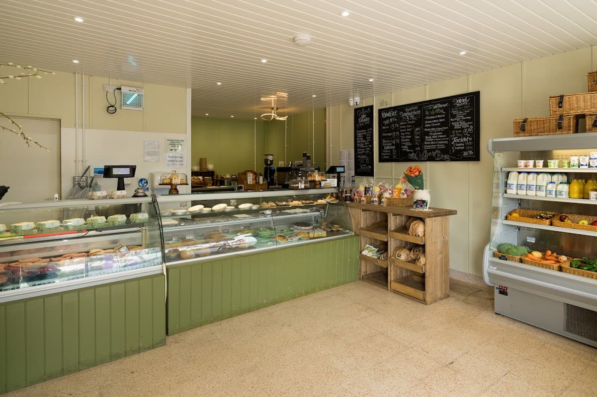 Interior of Gilberts Deli featuring display cases, wooden shelves, a chalkboard menu, and a variety of food products.