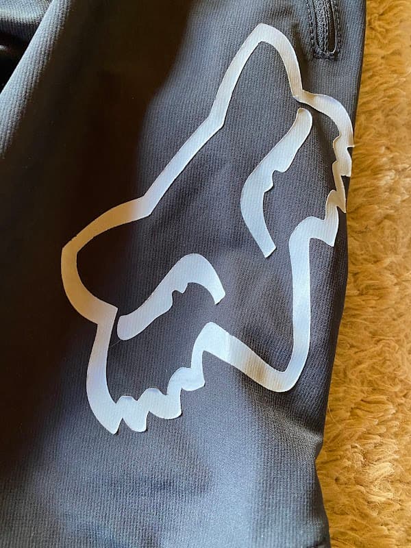 Black fabric featuring a large white fox logo, possibly related to mountain biking or outdoor sports.