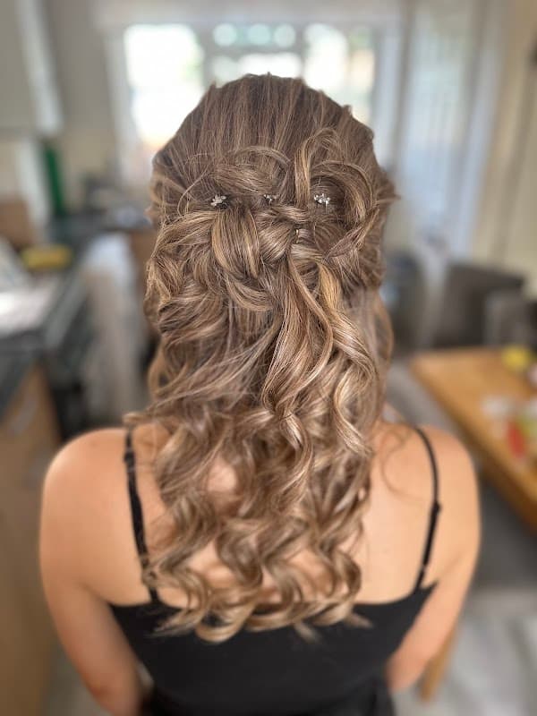 Long, wavy hair styled with elegant curls and decorative clips, seen from the back in a bright, modern interior.