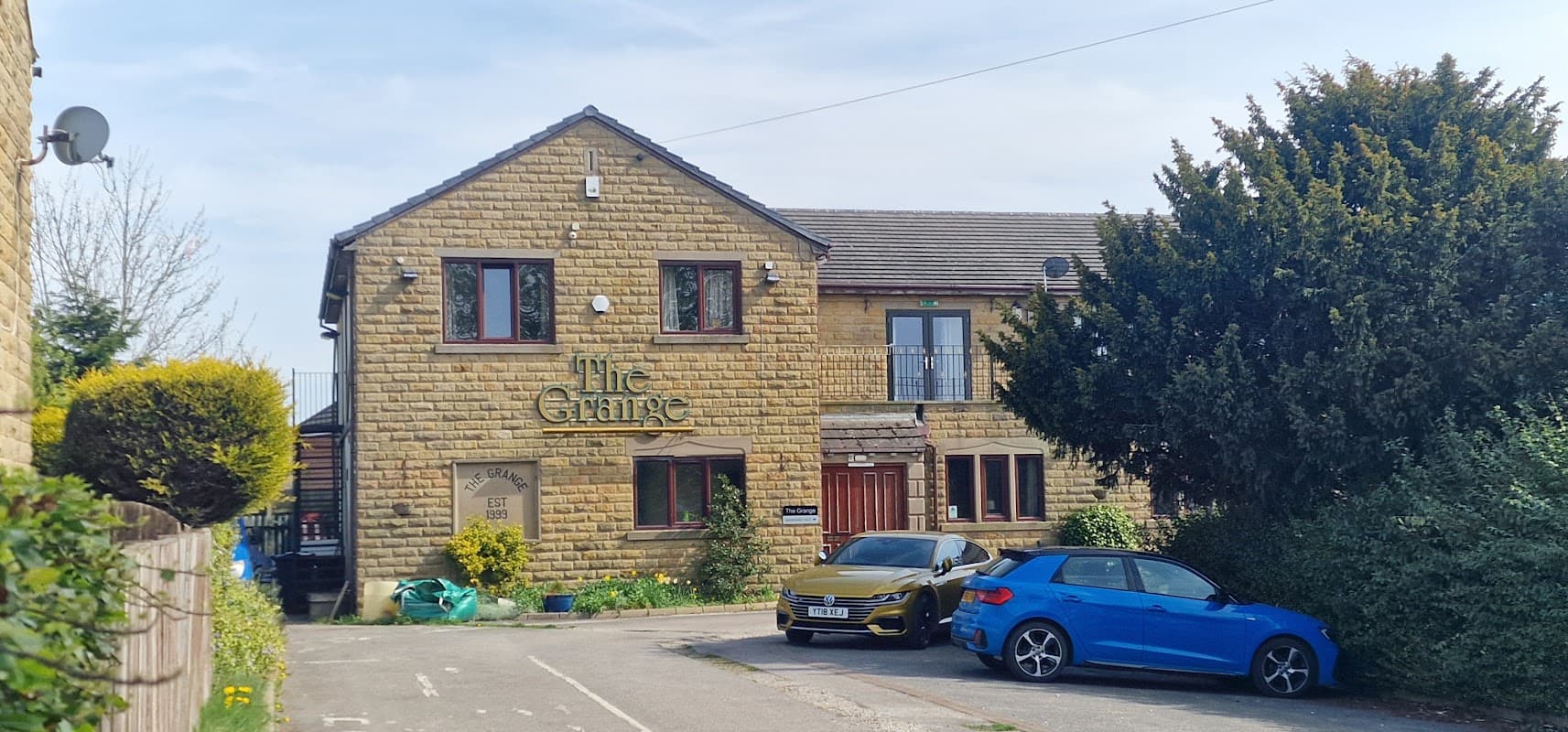The Grange bar features a stone exterior, green shrubs, and parked blue cars in a sunny Yorkshire setting.