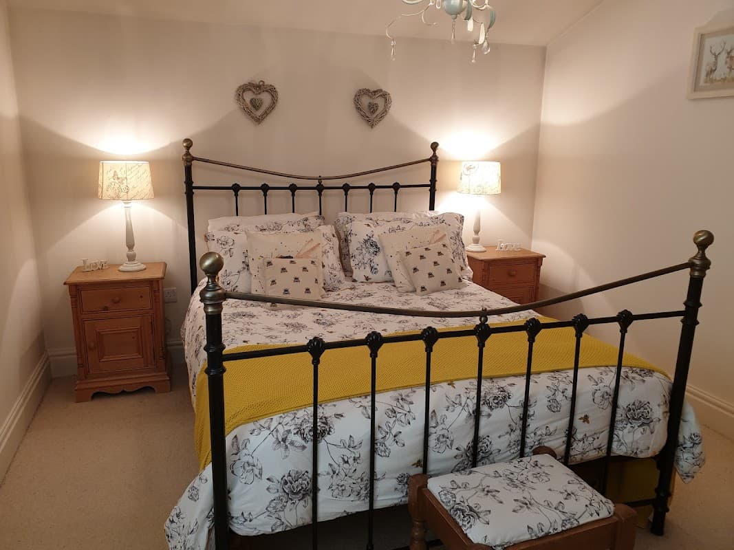 Cozy bedroom with an iron bed, floral bedding, wooden nightstands, and decorative lamps in a warm, inviting atmosphere.