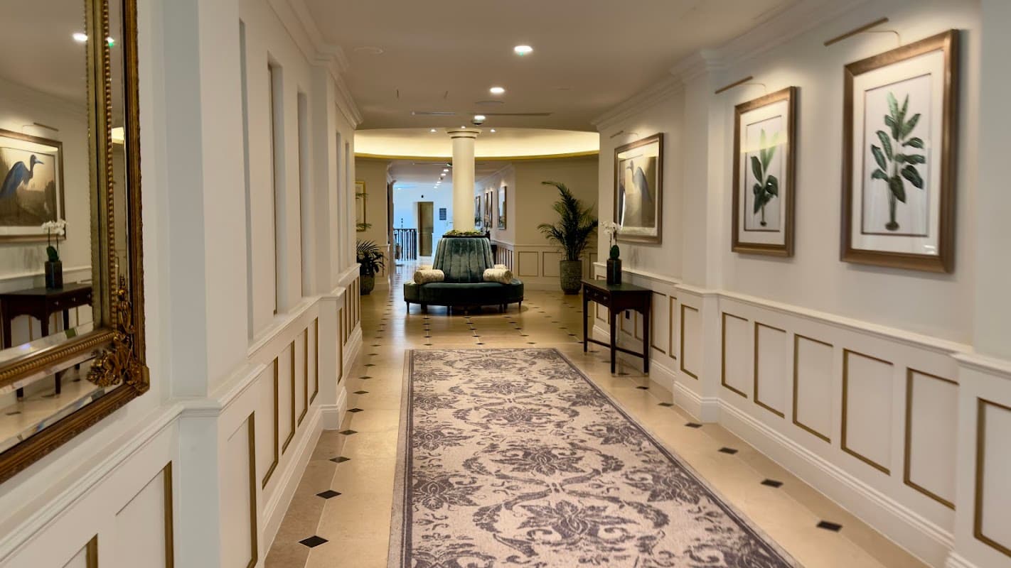 Elegant hallway featuring framed botanical art, a decorative fountain, and a plush rug at Three Graces Spa, Grantley Hall.