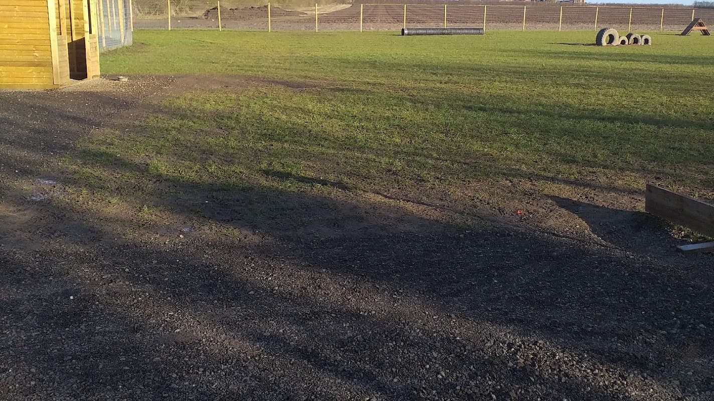 Expansive grassy area with gravel paths, wooden structure on the left, and fenced perimeter in Driffield, Yorkshire.