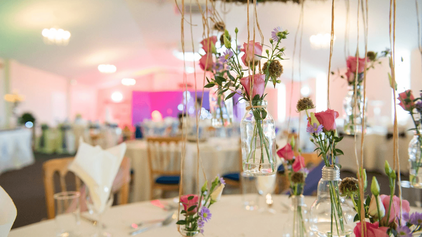 Hanging flower arrangements in glass jars adorn elegantly set tables at Driffield Showground event space.