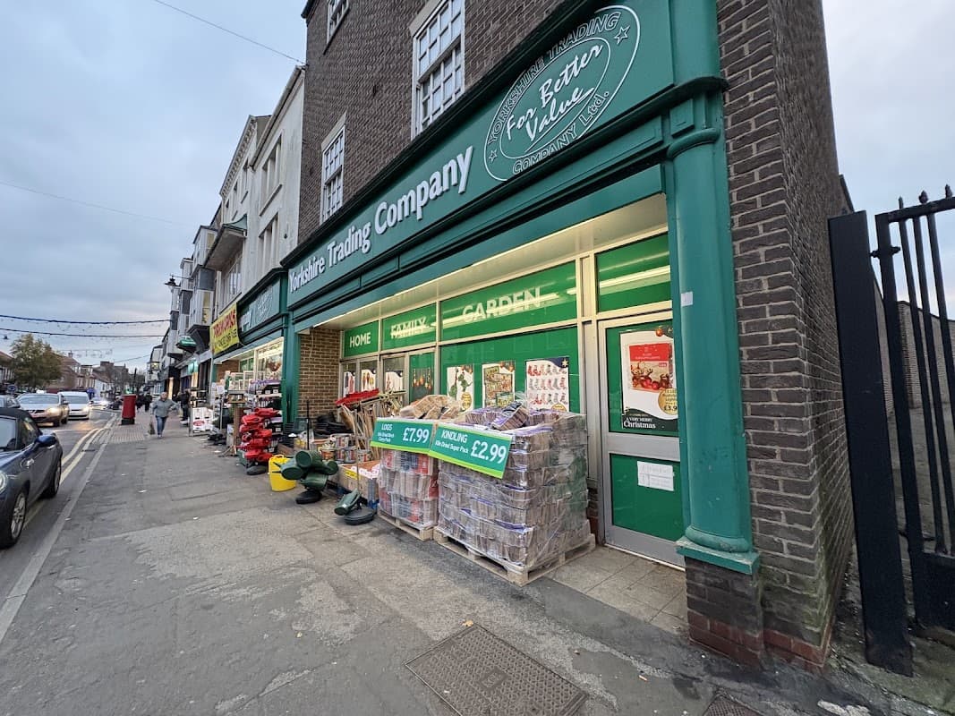 Yorkshire Trading Company storefront with green signage, displays of garden supplies, and a sidewalk with shoppers.