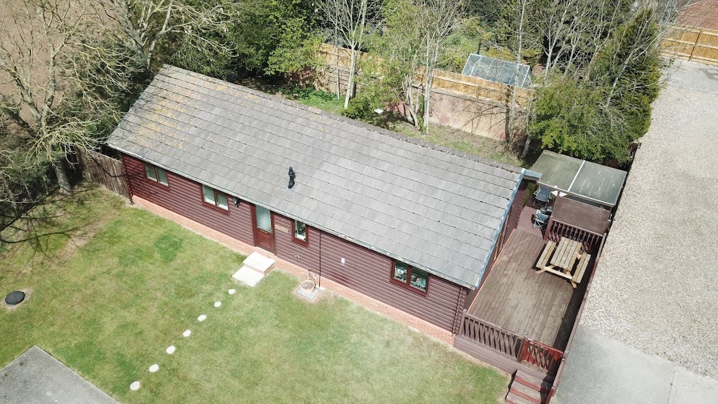 Aerial view of Great Hatfield Lodges featuring a wooden lodge, green lawn, and surrounding trees.