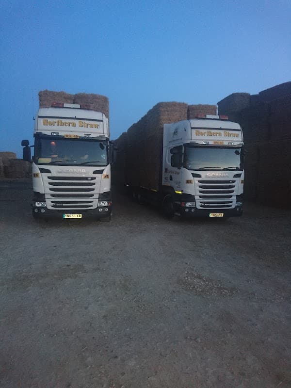 Two Scania trucks loaded with bales of straw parked in a gravel area at Northern Straw Co Ltd, Great Heck, Yorkshire.
