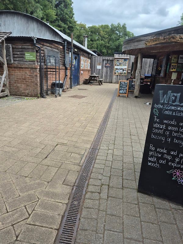 Pathway leading to the Ecclesall Woods Visitor Centre with wooden buildings and a chalkboard sign.