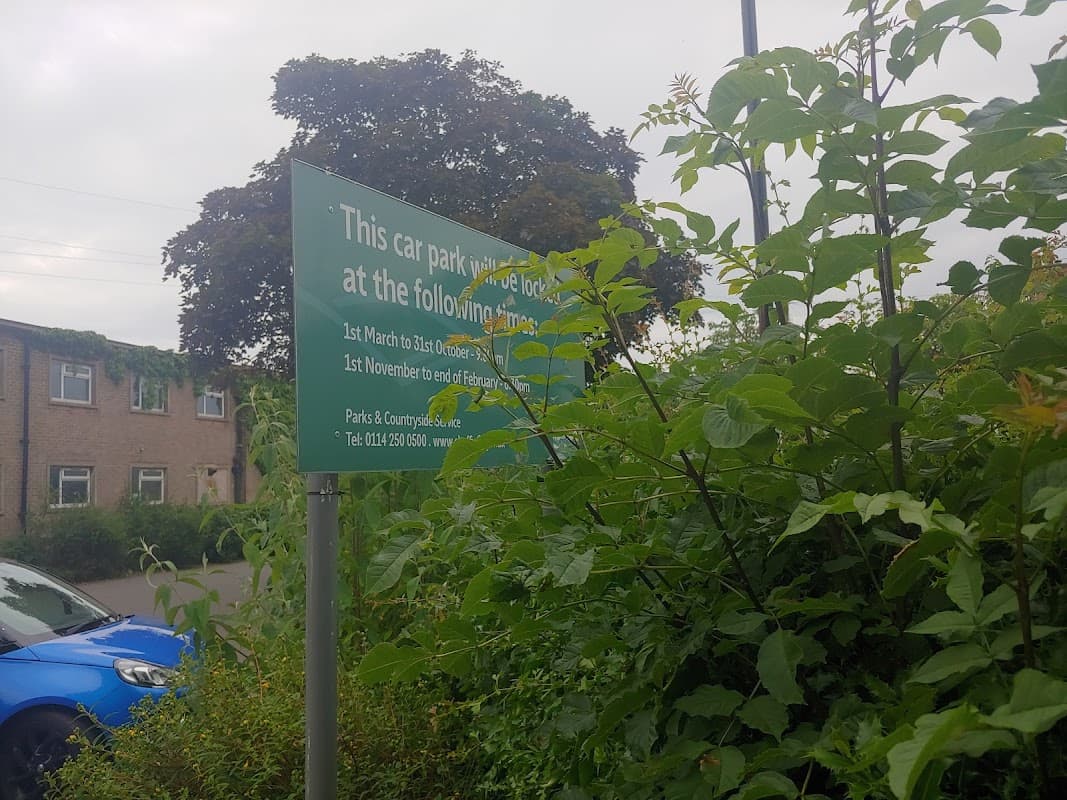 Sign indicating free parking at Graves Park Pavilion, surrounded by greenery and a blue car parked nearby.