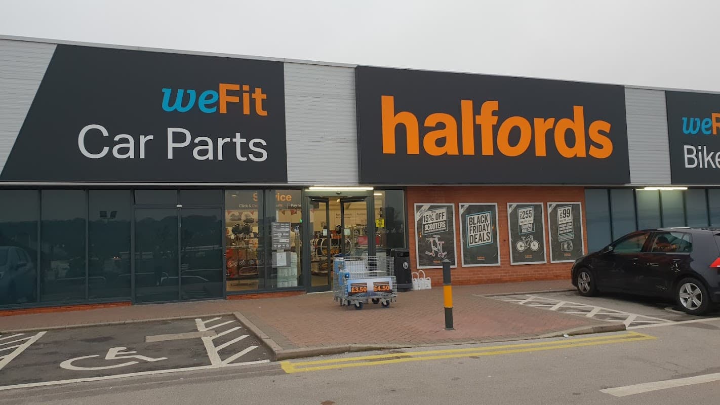 Halfords store front in Chesterfield featuring signage for car parts and bike services, with shopping carts outside.