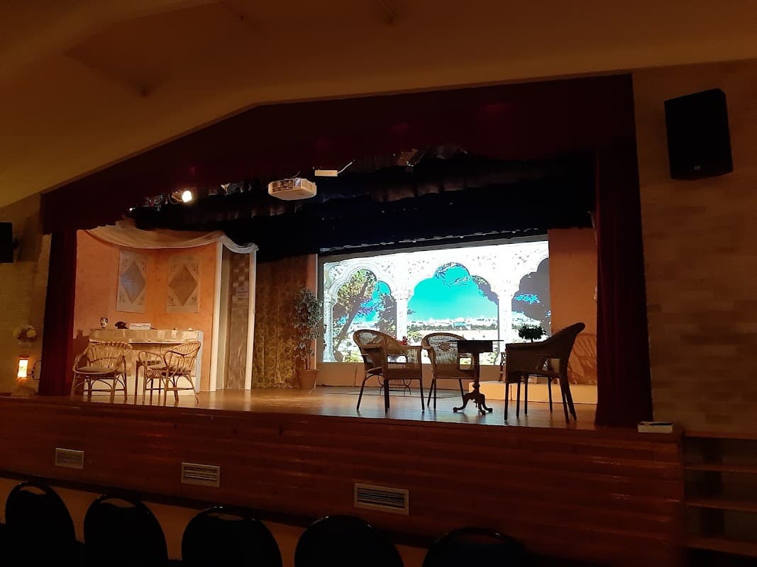 Stage setup at Grenoside Community Centre with chairs, tables, and a decorative backdrop featuring arches and greenery.