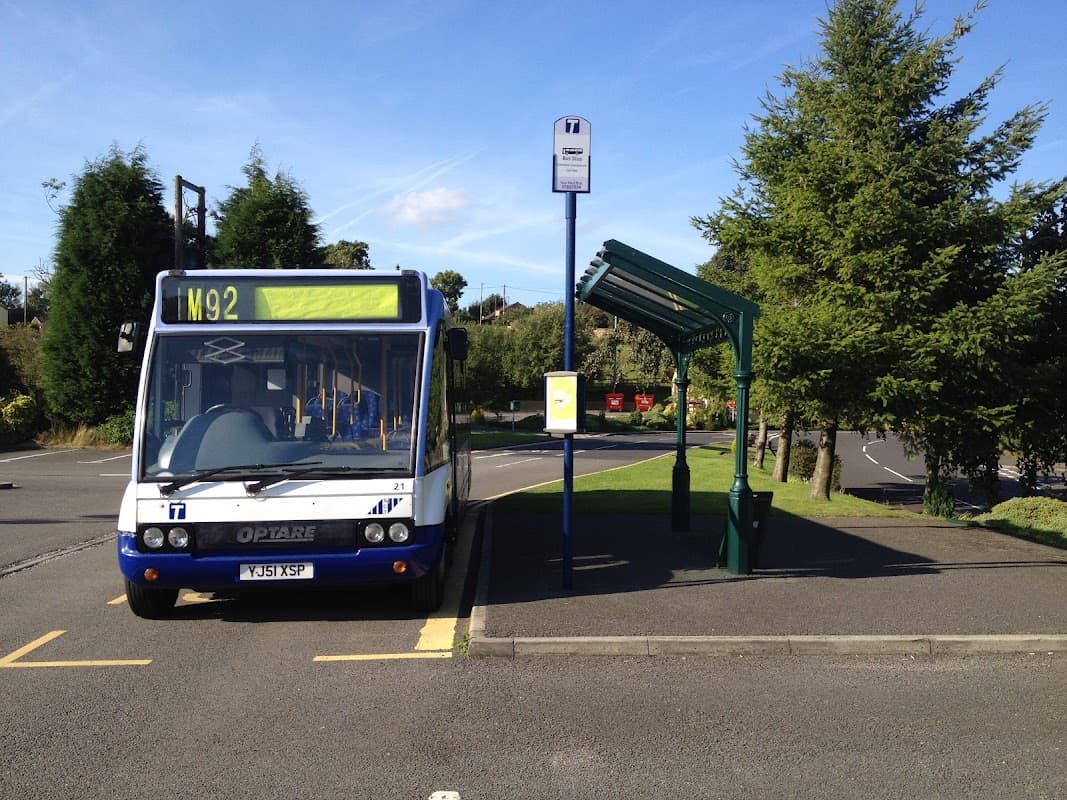 Bus stop with an M92 bus parked, surrounded by trees and a car park at Grenoside Crematorium in Yorkshire.