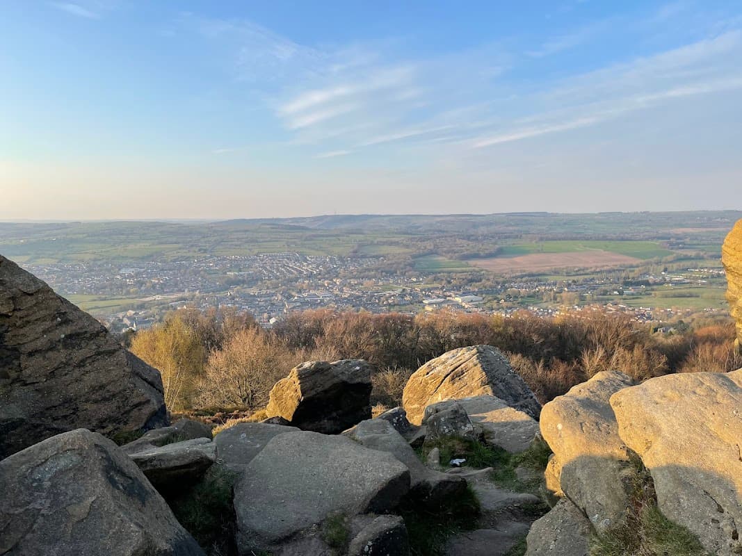 Scenic view from Surprise View Car Park, showcasing rolling hills, a valley, and distant fields under a blue sky.