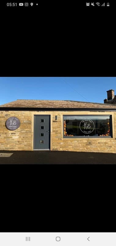 The Hair Barn features a stone exterior, large windows with circular signs, and a modern door under a clear blue sky.