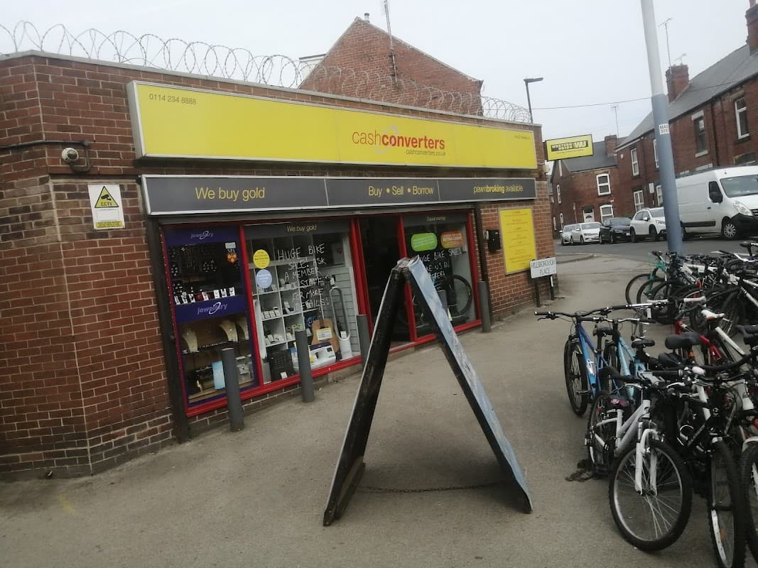 Jewellery shop with a sign reading "We buy gold," surrounded by bicycles and barbed wire on the building.