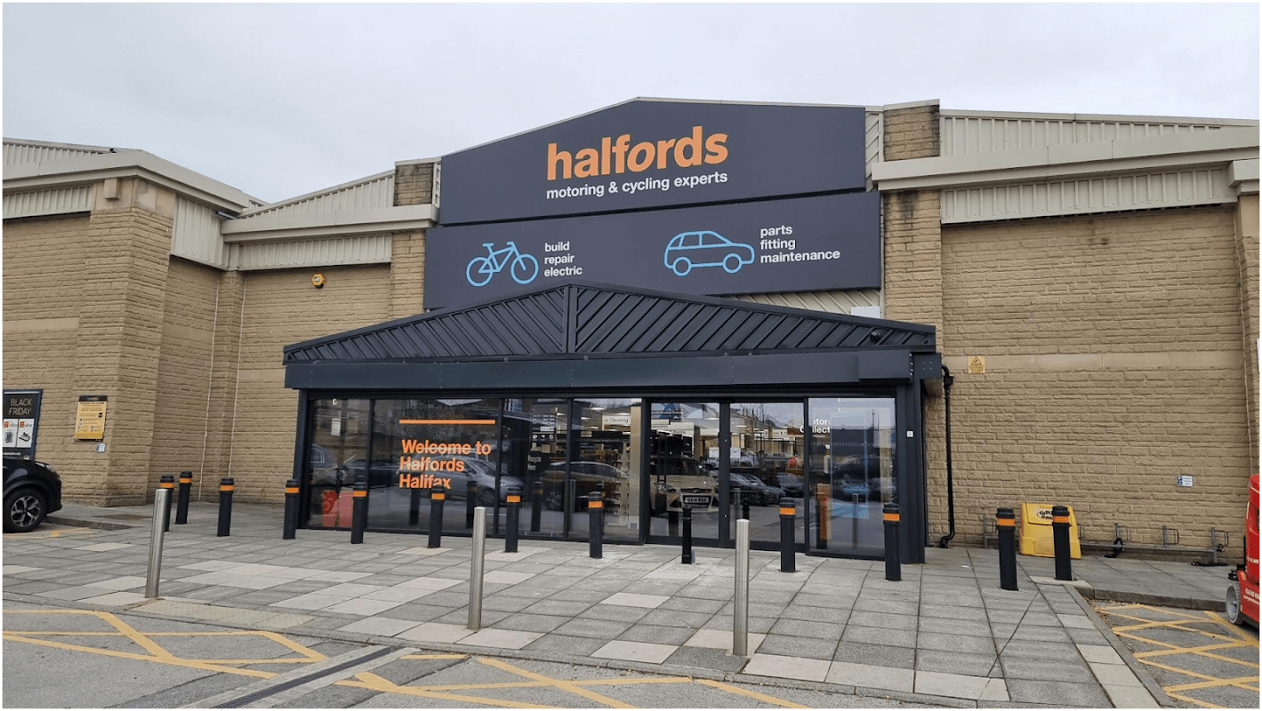 Entrance to Halfords store in Halifax, featuring signage for cycling and automotive services, with a modern facade.