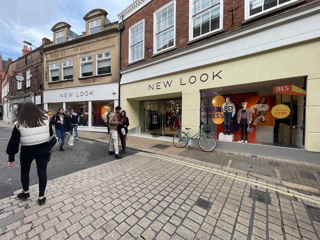 "New Look clothing store in Halifax, featuring a modern facade and shoppers outside on a cobblestone street."