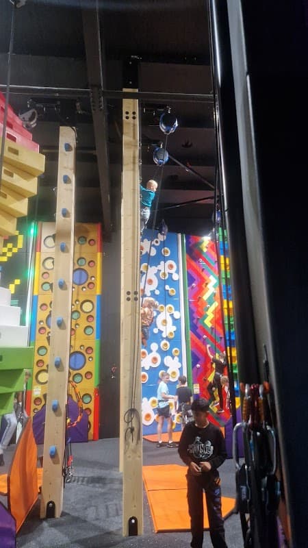 Indoor climbing area with colorful walls, climbing holds, and people engaged in climbing activities.