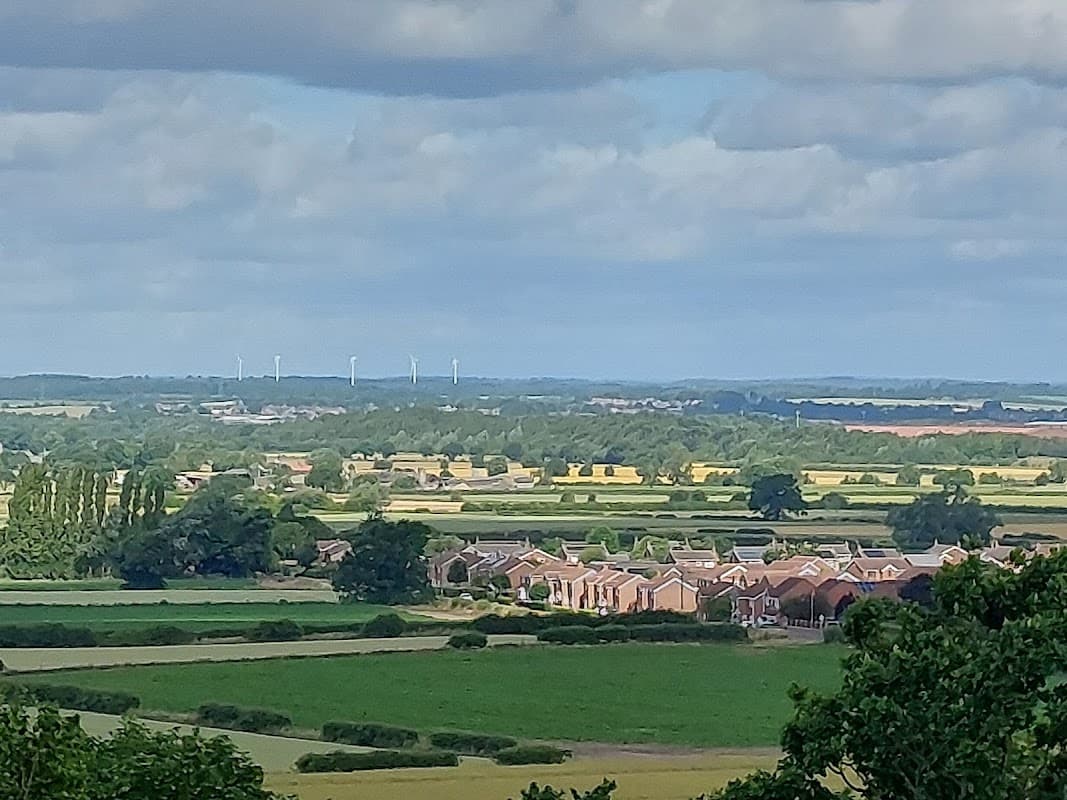 Rural landscape with fields, houses, and wind turbines under a partly cloudy sky in Hambleton, Selby, Yorkshire.