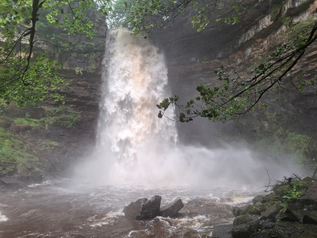 A powerful waterfall cascading over rocky cliffs, surrounded by lush greenery and mist rising from the water.