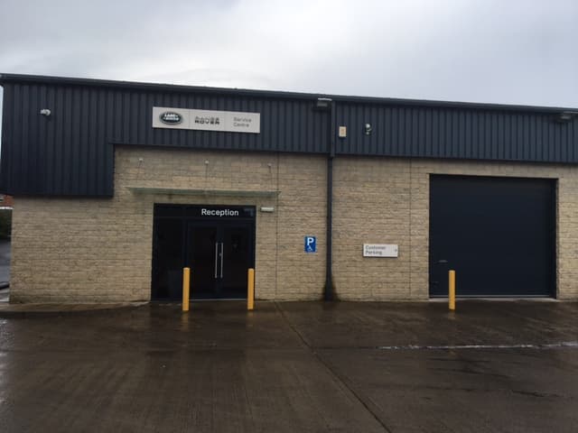 Lloyd Land Rover Leyburn Service Centre with a reception entrance and large garage door, set in a stone building.
