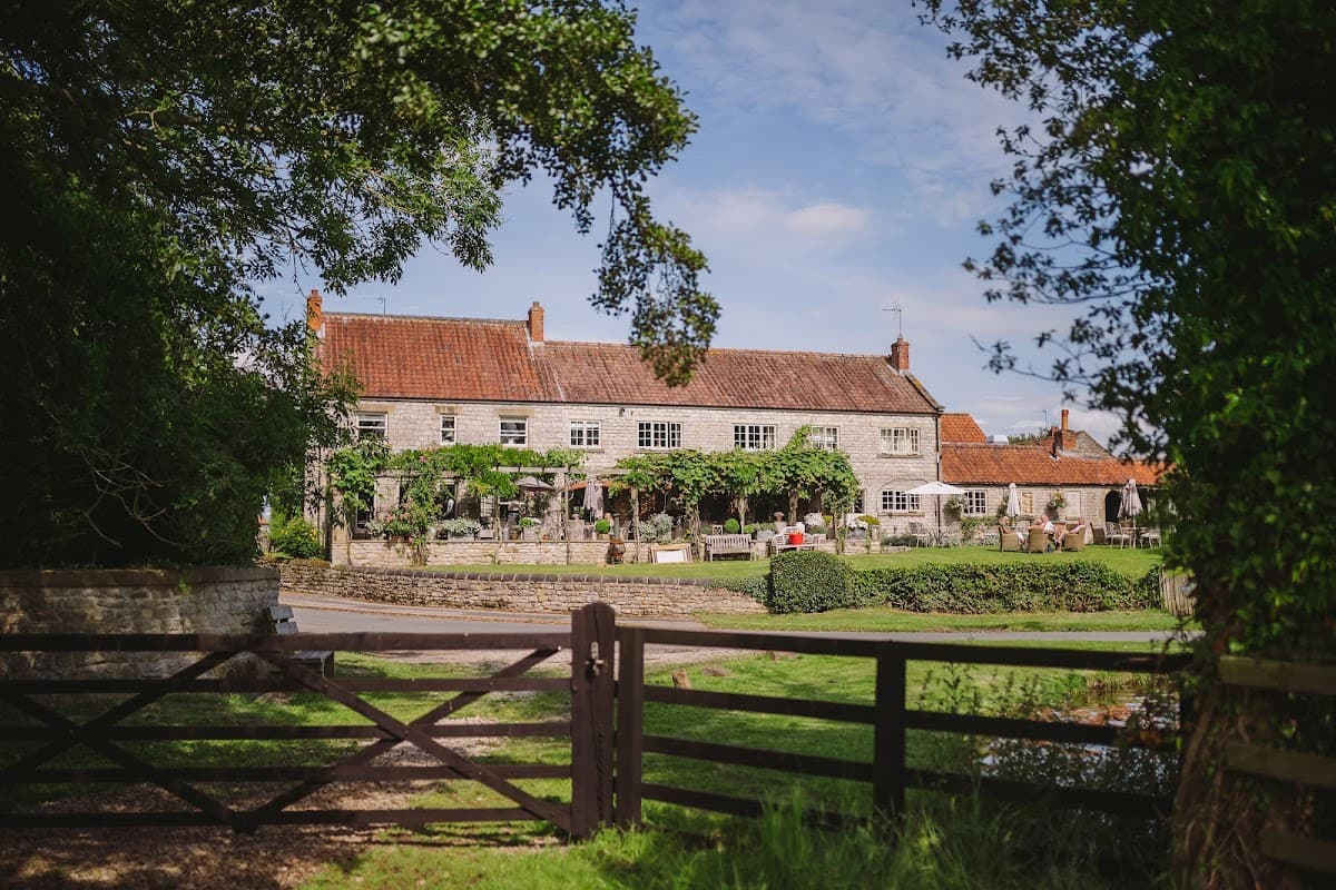 The Pheasant Hotel, a charming stone building with a red-tiled roof, surrounded by greenery and a peaceful landscape.