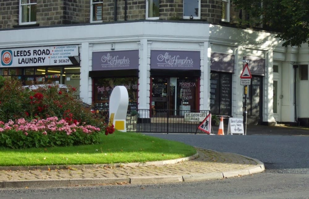 Ake & Humphris Wine & Beer Merchants storefront with signage, surrounded by flowers and nearby laundry service.