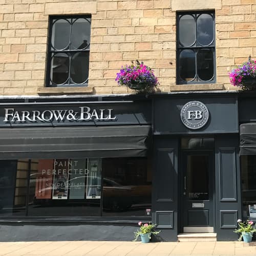 Farrow & Ball showroom in Harrogate with stone facade, large windows, and colorful flower baskets.