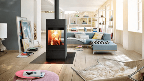 Modern living room featuring a black fireplace, cozy blue sofa, and stylish decor with natural light streaming in.
