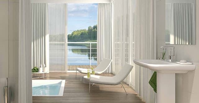 Modern interior featuring a bright bathroom with a sink, lounging chairs, and large windows overlooking a scenic view.