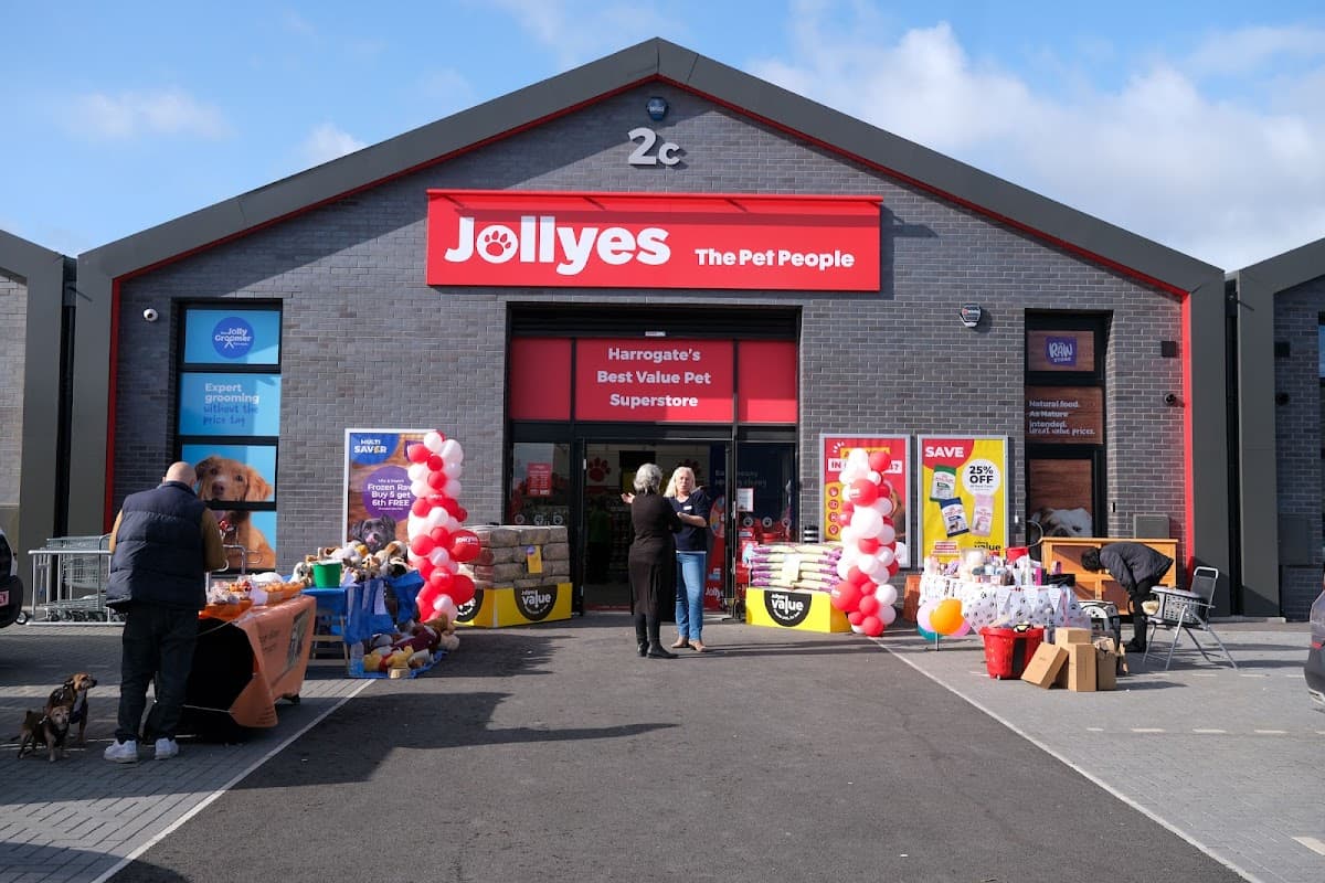 Exterior of Jollyes pet shop in Harrogate, featuring colorful banners, balloons, and pet supplies displayed outside.