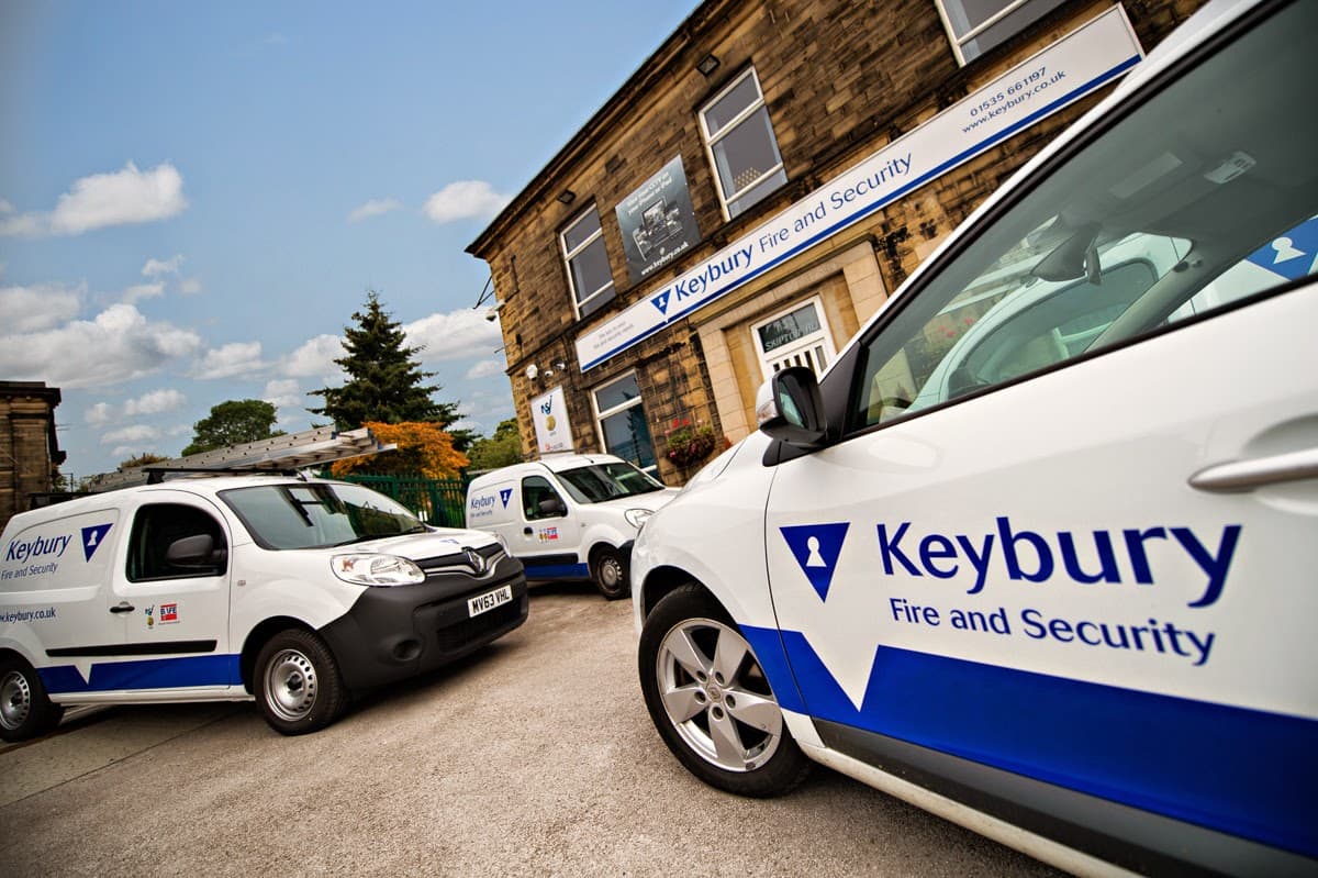 Keybury Security Systems vehicles parked outside a stone building with visible signage in Harrogate, Yorkshire.