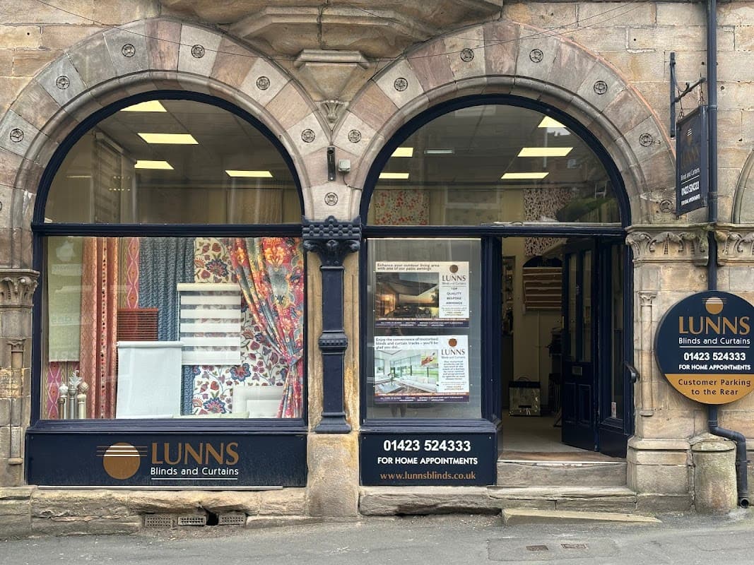 Storefront of Lunns Blinds & Curtains featuring colorful fabric displays and a welcoming entrance in Harrogate.
