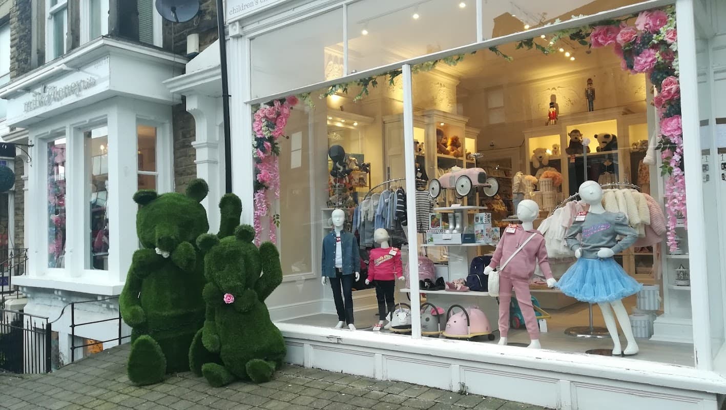 Colorful storefront of Milk & Honey, featuring mannequins in children's clothing and large green bear sculptures outside.